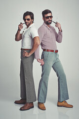 We know we're groovy. Studio shot of two men standing together while wearing retro 70s wear and...