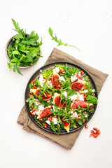 Fresh summer fig salad with white cheese, nuts, arugula and jam dressing on white table background, top view, copy space