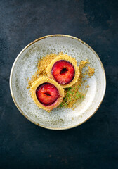 Traditioneller österreichischer Zwetschgenknödel mit einer Backpflaume im Teigmantel und Butterstreuseln serviert als Draufsicht in einer Nordic Design Schale 