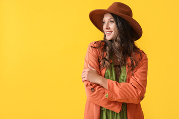 Portrait of beautiful smiling woman in stylish autumn clothes on yellow background