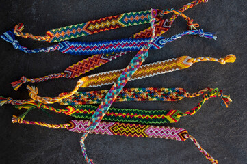 Handmade homemade colorful natural woven bracelets of friendship on gray frozen background,...