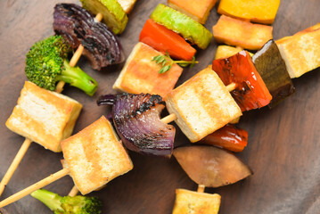 Plate with grilled tofu cheese skewers on table, closeup