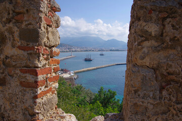 View of the ship through a window in the fortress wall in Alanya. Turkey.
