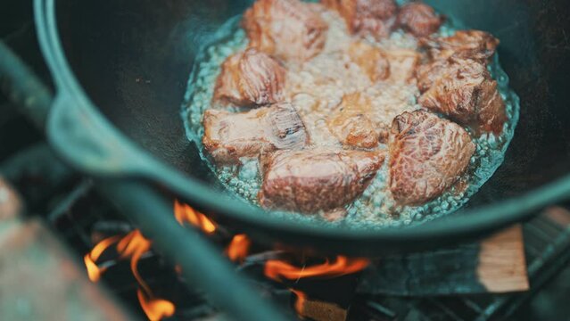 Meat is cooked in cauldron on fire. Step by step cooking of Pilaf.