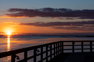 Fototapeta na wymiar Sunrise in Apalachicola, Florida with a silhouette of the railing of a pier.