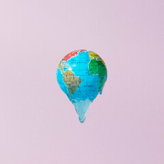 Globe or planet earth with leaking light blue glitter slime against purple background. Creative...