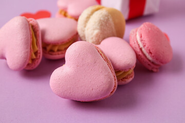 Tasty heart-shaped macaroons on purple background, closeup