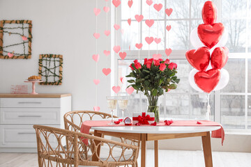 Glasses of champagne, engagement ring and flowers on dining table in room decorated for Valentine's day