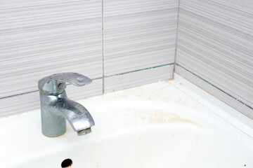Water tap in corner with rusty dirty sink close up. chrome faucet wash basin. White ceramic washing...