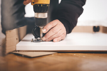 Man unpacking and assembling set of three drawers