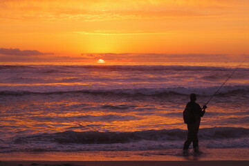 silueta de pescador amateur en la puesta de sol, pesca deportiva, pesca recreativa en la playa