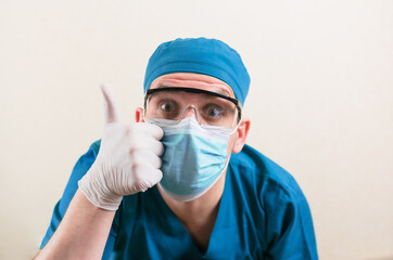 Fototapeta na wymiar Funny doctor with thumb up in blue surgeon suit and glasses on the yellow background isolated