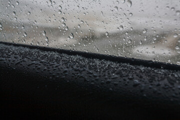 Car window with rain and snow