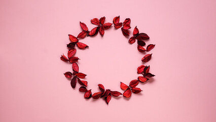 Flat lay round frame made of red flower petals on pink background. Top view. Copy space. Valentines day mothers day concept.