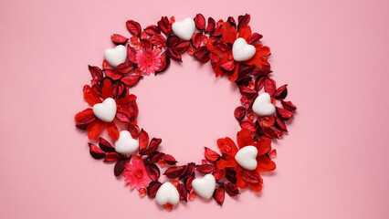 Floral wreath. Red pink flowers and white hearts composition on pink background. Round frame with empty space in the middle. Copy text. Valentines day Mothers day flat lay.