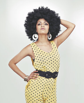 Disco diva with attitude. Cropped shot of young woman wearing a 70s retro jumpsuit striking a pose in studio.