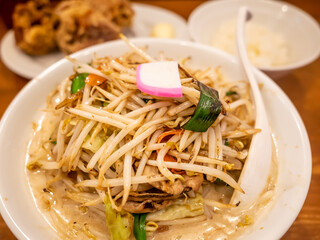 a ball of ramen with a lot of bean sprouts, a plate of fried chickens, and a ball of white rice in ramen restaurant