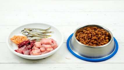 Cat food. Feeding bowls with natural fresh raw food and kibble for cat on wooden background. 