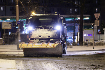 Pojazdy pług i piaskarka na drodze po nocnych opadach śniegu w mieście i ruch pojazdów.  - obrazy, fototapety, plakaty