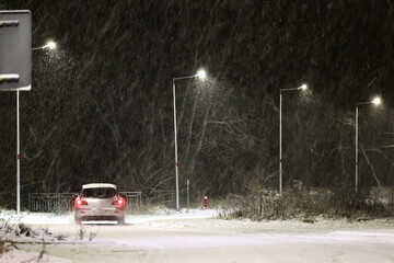 Pojazdy pług i piaskarka na drodze po nocnych opadach śniegu w mieście i ruch pojazdów.  - obrazy, fototapety, plakaty