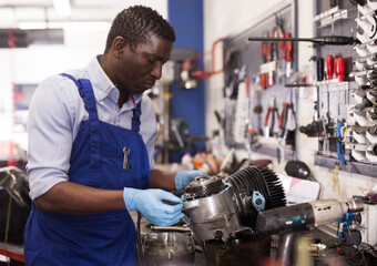 Fototapeta na wymiar African american worker in overalls inspects a motorcycle engine. High quality photo