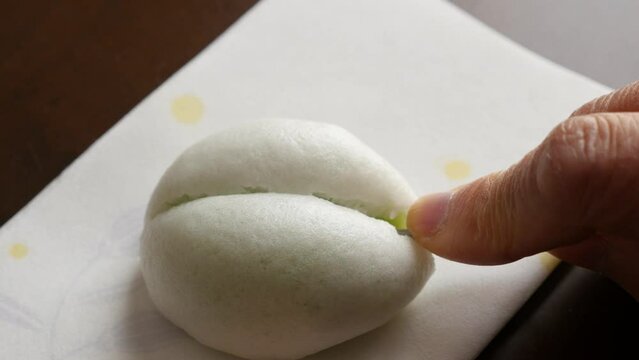 懐紙に置いた薯蕷饅頭を菓子楊枝で二等分にする

