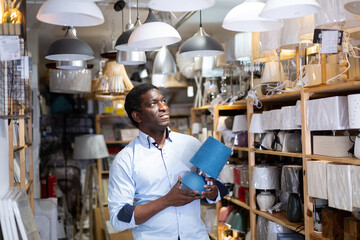 Fototapeta premium Man is choosing new table lamp for her home in the store
