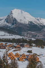 A picturesque vertical shot of the snowcapped French Alps mountains and the ski resort buildings on a cold winter day (La Joue du Loup, Devoluy)
