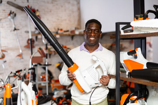 African-american man with leaf blower standing in gardening tool store.
