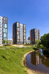 New modern residential apartment buildings near the lake surrounded by green trees and grass