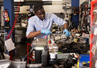 African american worker repairing a motorcycle engine in a garage. High quality photo