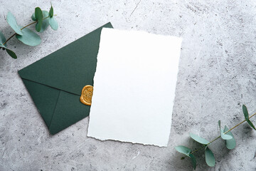 Elegant wedding stationery set. Wedding invitation card template and green envelope on concrete background. Flat lay, top view, copy space. - obrazy, fototapety, plakaty