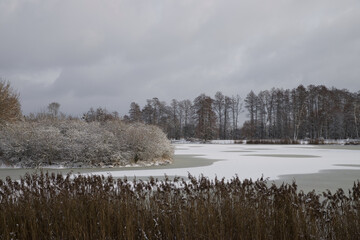 Winter landscape with a frozen pond partially covered with snow.