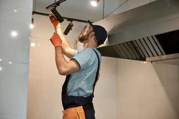 Repairman fixing ceiling lamp in cafe kitchen