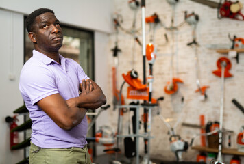 African-american man standing in salesroom of gardening tools store.