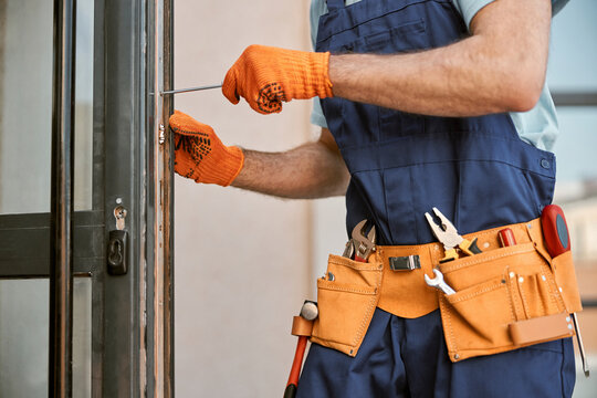 Male hands in gloves repairing door in house