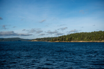 View of a vibrant blue sky above the San Juan Islands and the North Cascades mountain range from the Anacortes Ferry in Washington.