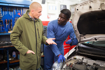 The mechanic communicates with the client about his car at auto car repair service center