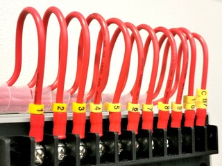 A row of red pvc cables connection with markers.