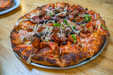 Freshly baked pizza with salami, sausages, meat, cheese, olives, pepper. 