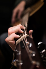 Person playing the acoustic guitar close up. Hands playing the guitar strings portrait. Learning to play a musical instrument