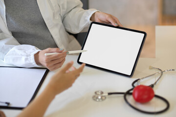Female doctor consulting the treatment plan on tablet to her patient.