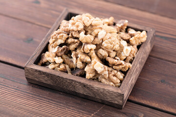 The wooden box is full of walnuts on the wooden background
