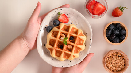 A female holding a waffle plate over white table