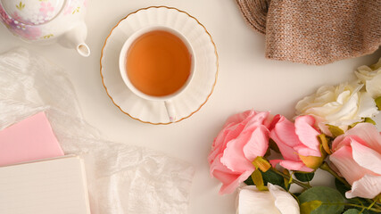 Feminine compositions background with tea cup and decor on white table.