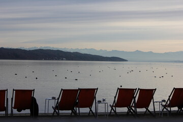 deck chairs in front and the lake starnberg with view on alps
