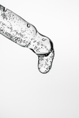 Transparent pipette with cosmetics on a light background.