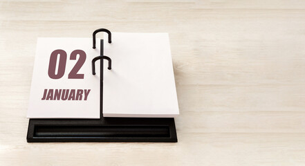 january 2. 2th day of month, calendar date. Stand for desktop calendar on beige wooden background. Concept of day of year, time planner, winter month
