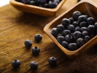 Fresh blueberries in brown square bowls and on the table. Wooden texture. Cooking, vitamins, diet food, medicine, fitness. Close-up. There are no people in the photo.