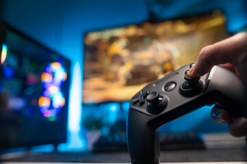 A gamer plays video games with friends at home in a room with a gamepad. Sitting in front of a big screen TV. Games, video games, game strategy, entertainment, recreation, hobby, sports.